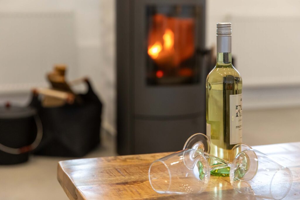 Nordseekaten Ferienwohnung Gästekate Weingläser mit Kamin im Hintergrund